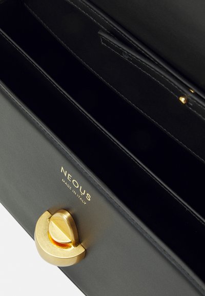 Čierna kožená kabelka so zlatými doplnkami, s oválnym uzáverom a vnútornými oddeleniami na organizáciu nevyhnutností. Logo je vyrazené vo vnútri.