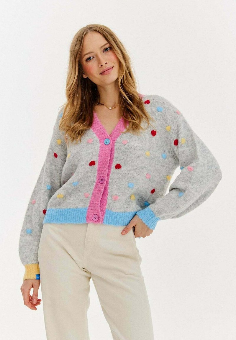 Szary kardigan z wielokolorowymi kropkami, różowym zapięciem na guziki z przodu oraz ryflowanymi niebieskimi i żółtymi mankietami. Miękka faktura i luźny krój.