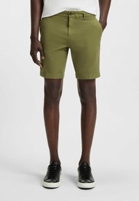 Olive green shorts with a straight cut, waistband with a button closure, and cuffed hem. Worn with black sneakers on a plain background.