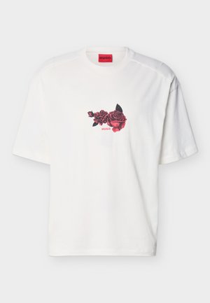 T-shirt blanc à manches courtes avec un motif de rose rouge et noire et le texte rouge "HUGO" sur la poitrine, sous une étiquette de marque rouge à l'intérieur du col.