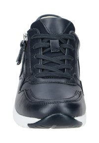 Zapatilla de cuero negra con paneles de malla, que presenta un diseño de cordones en el frente, cremallera lateral y suela de goma blanca. Textura suave, estilo minimalista.