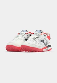 Bele športne čevlje z rožnatim podplatom in detajli. Vključujejo perforirane stranske panele, vezalke in oblazinjen podplat.