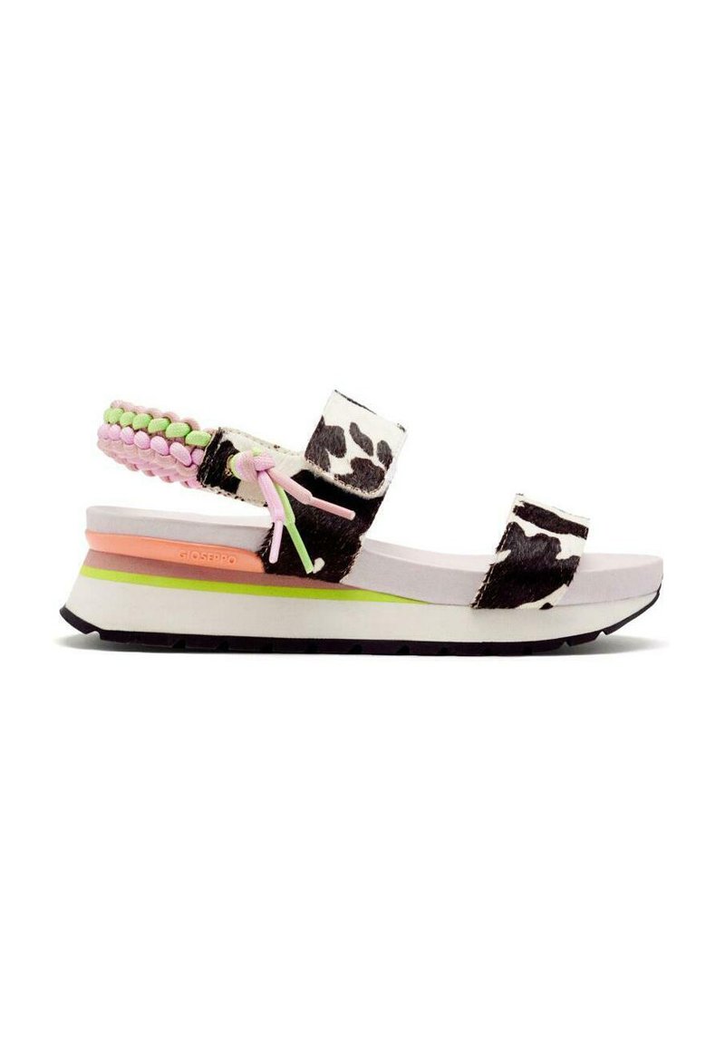 Sandalias de estampado de vaca en blanco y negro con acentos trenzados en rosa y verde, que presentan una suela blanca gruesa y elementos de diseño coloridos en capas.