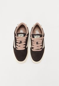 Black and tan Vans sneakers feature suede material, rounded toe, and cream-colored rubber sole with pink laces and logo on the tongue.