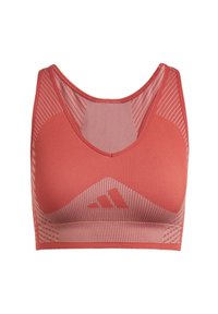 Sports bra in coral color, made of textured fabric with a breathable mesh design. Features a scoop neck and a logo on the front.