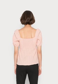 Blusa texturizada rosa com mangas bufantes e decote quadrado nas costas, apresentando um corpete franzido e um corte relaxado.