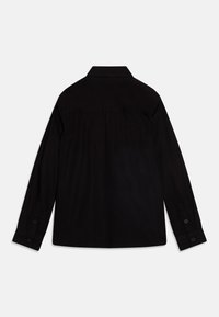 Svart långärmad skjorta med krage, knäppbara manschetter och detalj med ryggok. Tillverkad av slätt tyg med matt yta.