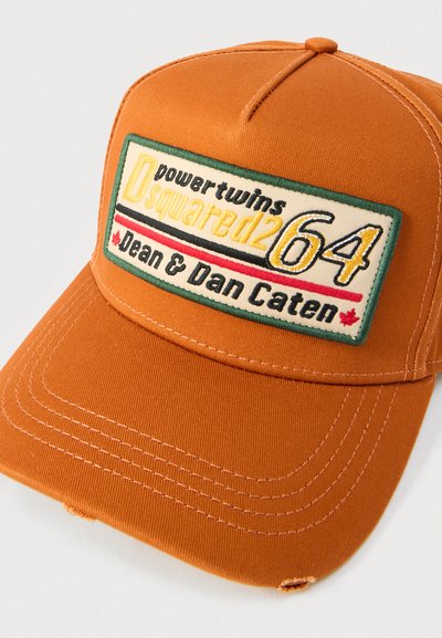 Orangefarbene Kappe aus strukturiertem Stoff mit einem rechteckigen, bestickten Patch, auf dem "Dsquared264" und "Dean & Dan Caten" in verschiedenen Farben zu sehen sind.
