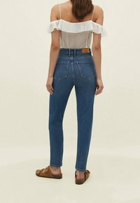 Hoog getailleerde, rechte blauwe spijkerbroek, denimstof, ontwerp met vijf zakken, voorzien van een leren label op de achterband.