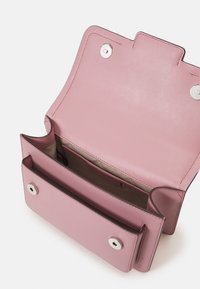 Růžová kožená peněženka s hladkým povrchem, máklapku a stříbrné kování. Uvnitř má vícero přihrádek pro organizaci.