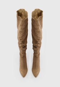 Stivali in suede beige a metà polpaccio, arricciati, con punta affusolata e rivestimento interno liscio, caratterizzati da una consistenza morbida e un design scomodo.