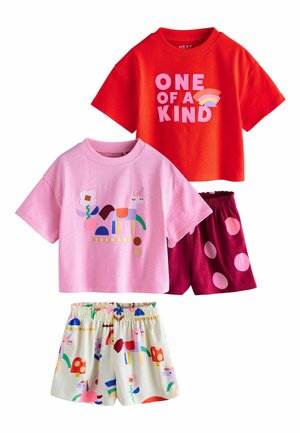 To sæt børnetøj: rød T-shirt med "ONE OF A KIND" og regnbue, pink T-shirt med enhjørning, kombineret med shorts med prikker og enhjørning-tryk.