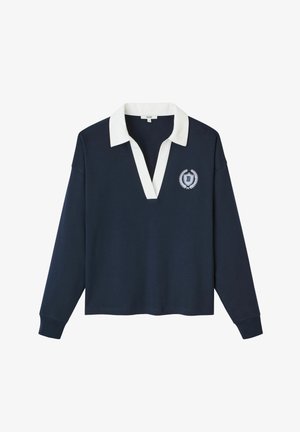 Pull navy avec un col contrastant blanc, à manches longues et en V. Présente un emblème brodé sur le côté gauche.