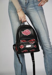 Sac à dos en cuir noir avec des motifs de nuages rouges, poche avant zippée et sangle réglable. Forme arrondie et poignée robuste.