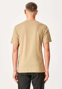 Beige kortærmet T-shirt med en simpel rund hals, lavet af blødt bomuld. Glat tekstur, ingen synlige mønstre eller accenter.
