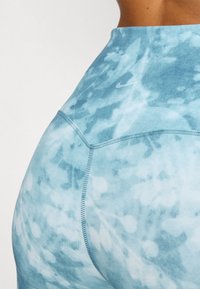 Magas derekú leggings világoskék tortúra mintával, rugalmas anyagból, lapos varratokkal, hátul egy kis Nike logóval.