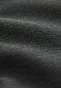 Gros plan sur un tissu noir texturé avec des fibres étroitement tissées et une surface douce et lisse présentant de légers plis.