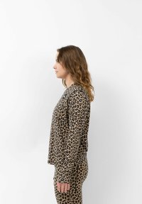 Langarmtop mit Leopardenmuster in Beige und Schwarz, hat einen lockeren Schnitt mit langen Ärmeln und wird mit passenden Leopardenmuster-Hosen kombiniert.