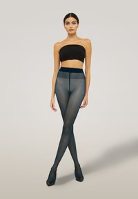 Genomskinliga svarta strumpbyxor med en slät, matt yta; högmidjad design med elastisk midja; modellen bär en svart bandeau-top och klackar.