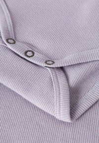 Helelavendel ribidega kangas ümarate kaelusega ja kolme metallist trukiga. Sile tekstuur kontrastse õmblusega detaile.
