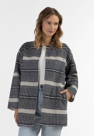 Giacca a motivi blu navy e crema con un taglio rilassato, apertura frontale, maniche lunghe e tasche. Realizzata in tessuto testurizzato con design geometrico.