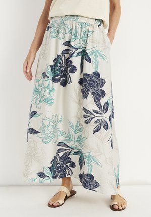 Hvide bukser med vide ben med blå og blågrøn blomsterprint, elastisk talje, båret med beige sandaler og en lys beige top.