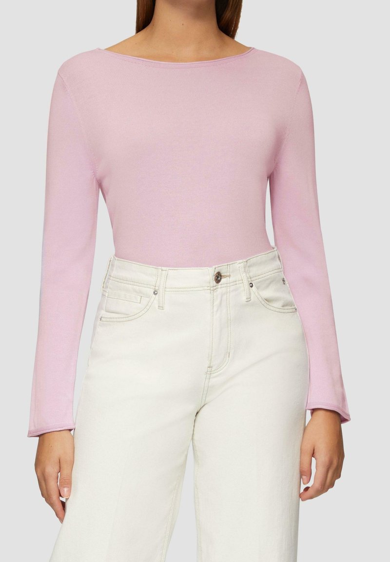 Jasnoróżowa bluzka z długim rękawem, o dekolcie w łódkę, prążkowanej fakturze i dopasowanym kroju, zestawiona z wysokim stanem off-white spodniami.