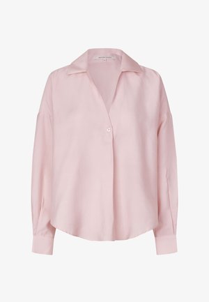 Vaaleanpunainen paita pehmeästä kankaasta, jossa on lovikoristeinen kaulus, nappikiinnitys ja pitkät hihat kalvosimilla. Yksinkertainen, klassinen muotoilu.