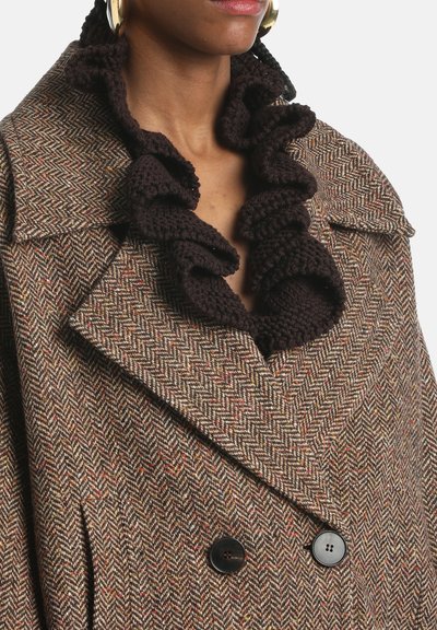 Brown herringbone coat with a ruffled black knit collar. Double-breasted design featuring large black buttons and textured fabric details.