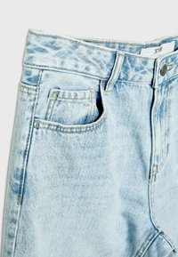 Jean en denim bleu clair acid-wash montrant la ceinture, le bouton, la passants de ceinture et les poches avant avec des coutures détaillées.