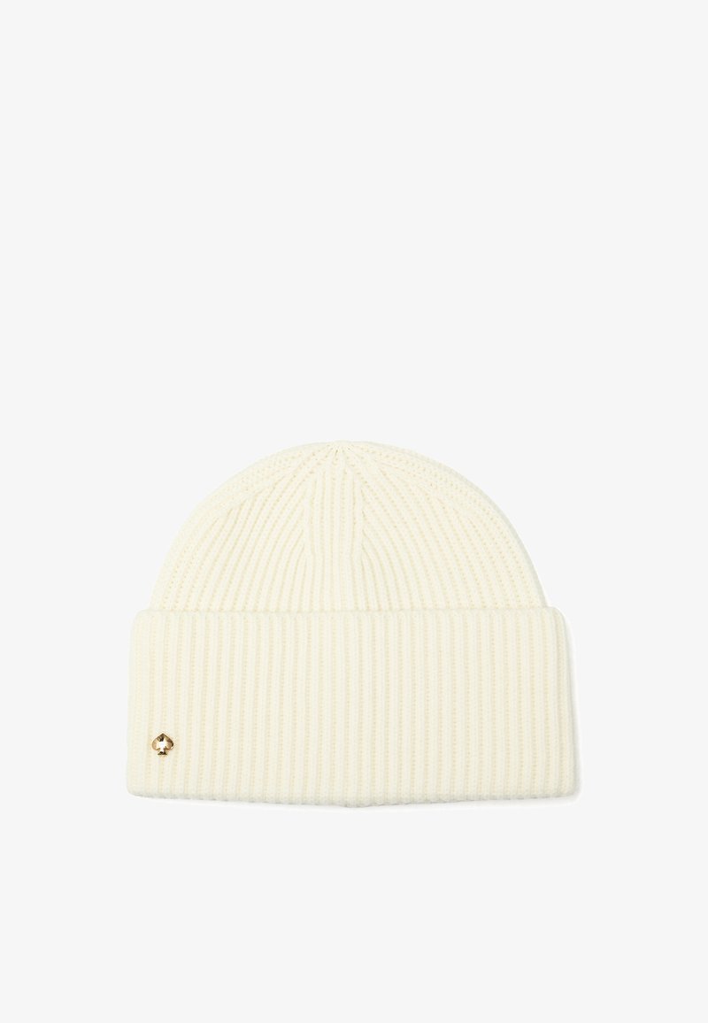Cremefarvet ribstrikket beanie med ombukket manchet og et lille metallisk spadeemblem på manchetens venstre side.