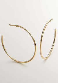 Pendientes en forma de aro de tono dorado con un acabado liso y brillante. Cada pendiente presenta una forma circular con un diseño delgado y abierto.