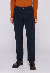 Pantalones de pana azul marino con un diseño de pierna recta, dos bolsillos frontales y un botón de metal en la cintura, con una textura suave.