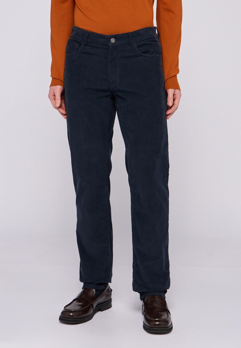 Pantalones de pana azul marino con un diseño de pierna recta, dos bolsillos frontales y un botón de metal en la cintura, con una textura suave.