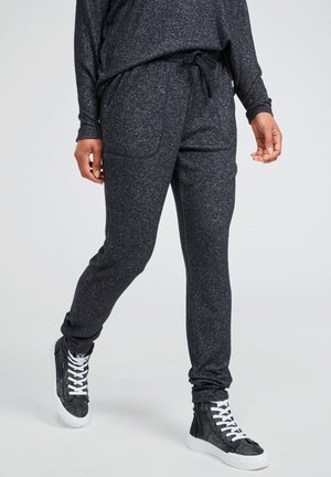 Black jogger pants with a heathered texture, elastic waistband, drawstring, and side pockets, paired with high-top sneakers.