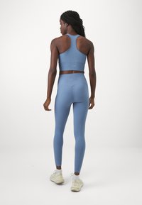 Ljusblå ribbad sport-bh och leggings-set, med en figurnära design, racerback-stil och mjuk textur, kompletterad av minimal märkning.