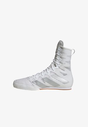 Zapatilla deportiva blanca de caña alta con rayas plateadas, diseño con cordones y suela texturizada sobre un fondo blanco.