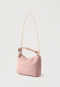 Sac à main en daim rose doux avec une bandoulière en chaîne dorée et une poignée rembourrée, posé sur un fond blanc uni.