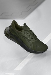 Grønn atletisk sneakers med overdel i teksturert mesh, runde snørebånd, polstret krage og en svart gummisåle, med en logo på siden.