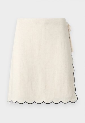 Jupe portefeuille écrue avec ourlet festonné souligné de noir, nouée à la taille sur le côté droit.