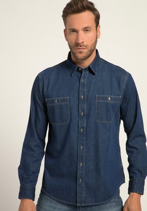 Camisa de mezclilla azul oscura con cierre de botón, dos bolsillos en el pecho y mangas largas. Presenta un cuello clásico y detalles de costura sutiles.