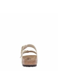 Beige sandal with three adjustable straps and a cork footbed. The sole is textured with a black rubber outer for grip and durability.