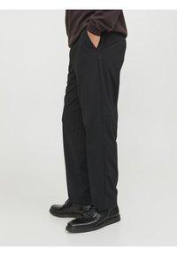 Pantalones negros hechos de una tela suave, con bolsillos laterales y un ajuste relajado, combinados con zapatos de cuero negros para un look pulido.