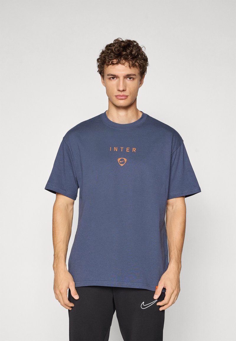 T-paita tummansinisestä puuvillasta, lyhyillä hihoilla; keskellä oranssilla "INTER" ja logo. Suora malli ja pyöreä pääntie.