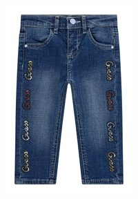 Jeans in denim blu scuro, con cinque tasche, chiusura a bottone e loghi "Guess" ricamati in vari colori lungo i lati.