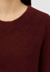 Maglione bordeaux a maglia con scollo rotondo. Il tessuto testurizzato presenta un sottile motivo a costine e una texture morbida e pelosa.
