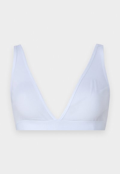 Λευκό bralette με βαθύ V-λαιμόκοψη, φτιαγμένο από μαλακό, ελαστικό ύφασμα. Διαθέτει ρυθμιζόμενους ιμάντες και λαστιχένια ζώνη με λογότυπο στο κάτω μέρος.