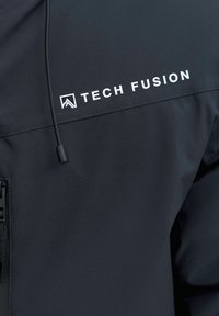 Juodas minkštas švarkas su priekiniais užtrauktukais, reguliuojama kapišonu ir baltu "TECH FUSION" logotipu viršutinėje kairėje krūtinės dalyje.
