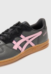 Zwarte leren sneaker met roze accenten, textuur bovenkant, zwarte veters, gumrubberen zool en "SKYHAND" branding aan de zijkant.