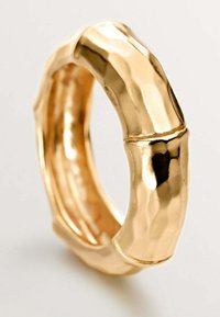 Anillo de oro con textura martillada, con un diseño inspirado en el bambú y bordes suaves y redondeados. Sin adornos visibles.